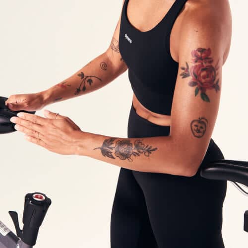 Bras tatoué d’une femme, main tendue au-dessus d’un vélo de cycling